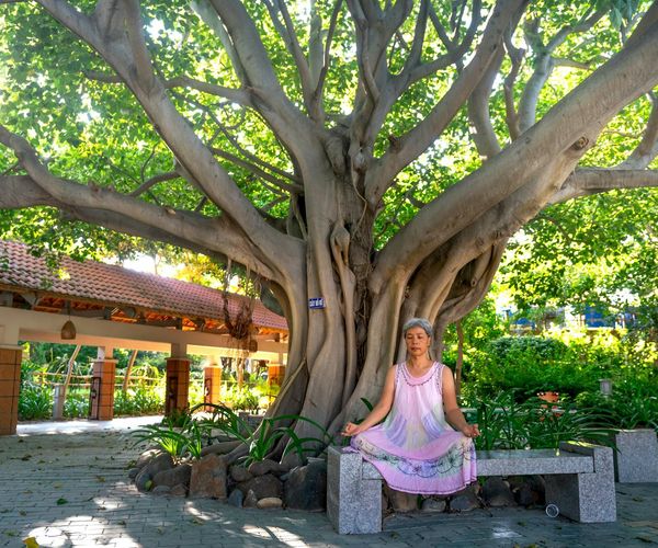 Smiling person stretching on a yoga mat with a serene background.